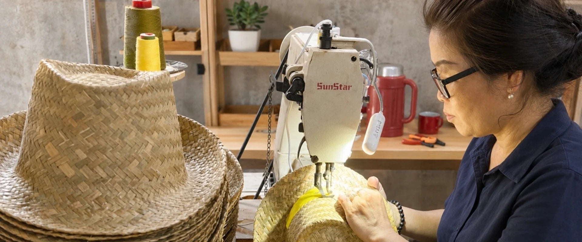 Worker sewing natural straw hats at CHATA Vietnam straw hat factory